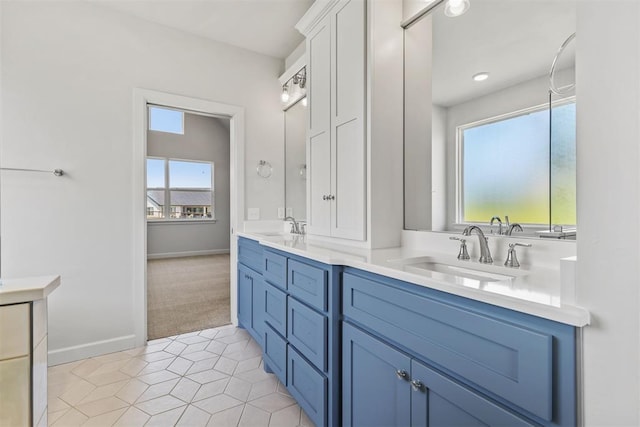 full bath with double vanity, baseboards, a sink, and tile patterned floors