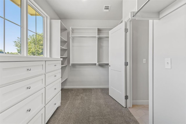 walk in closet with visible vents and light colored carpet