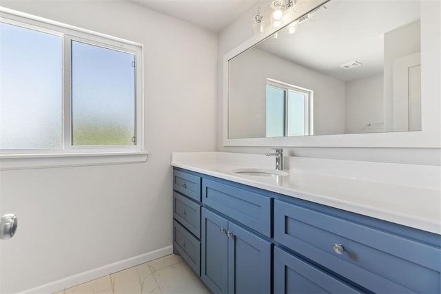 bathroom with marble finish floor, vanity, a wealth of natural light, and baseboards