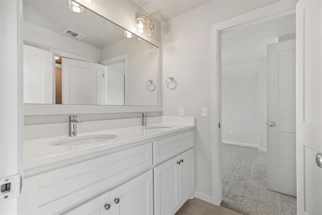 bathroom with double vanity, a sink, visible vents, and baseboards