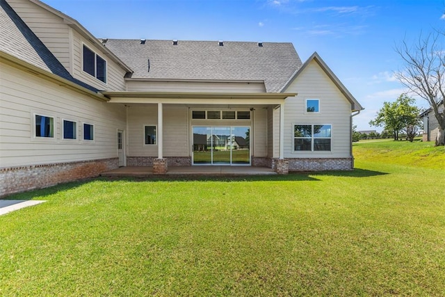 back of property with a yard, roof with shingles, and a patio