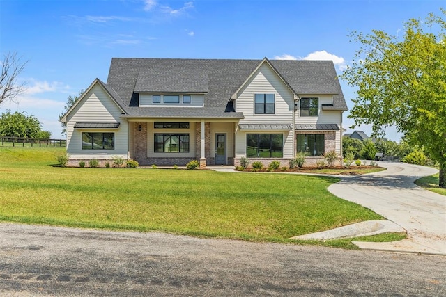 view of front of house with a standing seam roof, roof with shingles, metal roof, and a front lawn