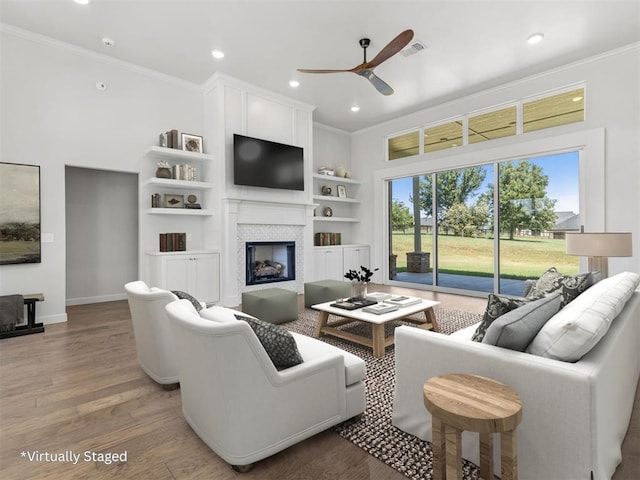 living room featuring a fireplace, wood finished floors, visible vents, and crown molding