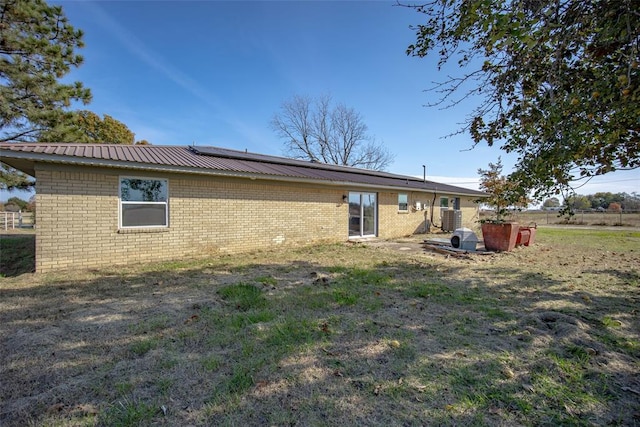 rear view of property featuring solar panels and a yard