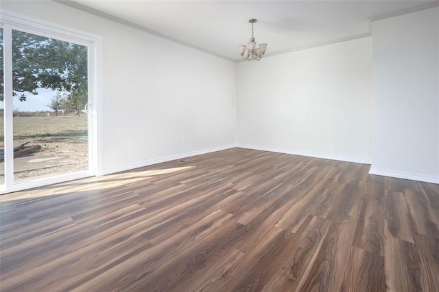 empty room featuring a chandelier, dark hardwood / wood-style floors, and ornamental molding