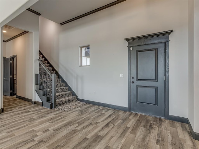 entryway with light hardwood / wood-style floors and crown molding