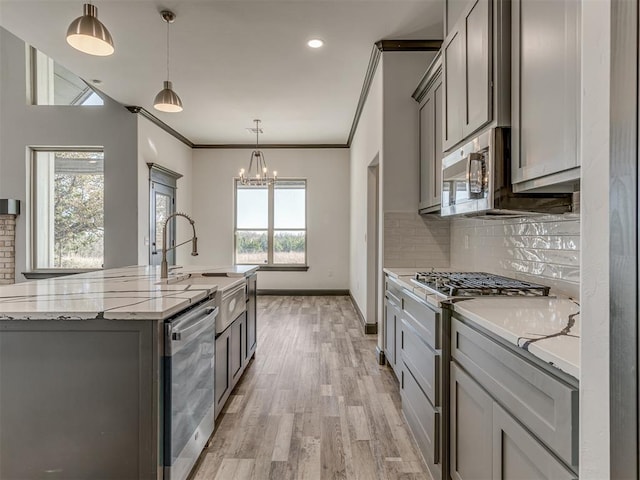 kitchen featuring light stone countertops, appliances with stainless steel finishes, gray cabinets, and hanging light fixtures