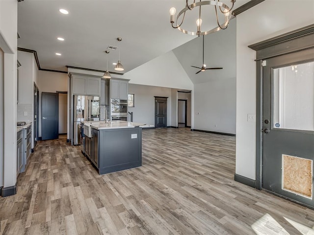 kitchen featuring pendant lighting, decorative backsplash, an island with sink, and hardwood / wood-style floors