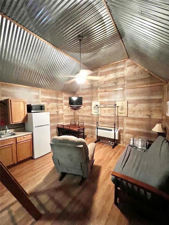 interior space featuring wooden walls, sink, light hardwood / wood-style floors, and vaulted ceiling