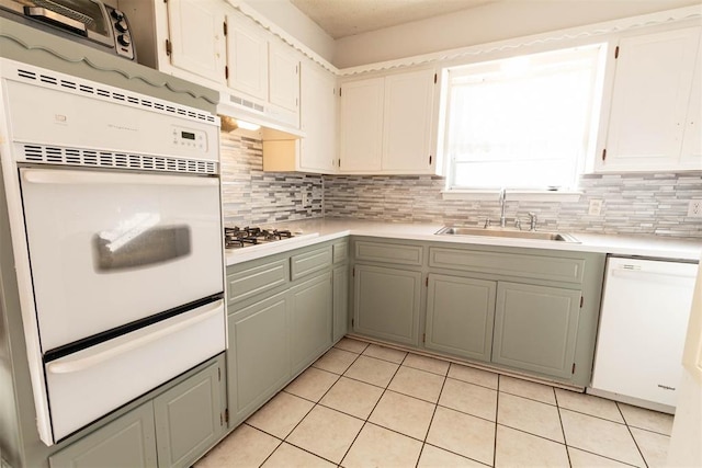 kitchen featuring backsplash, white appliances, sink, and light tile patterned floors