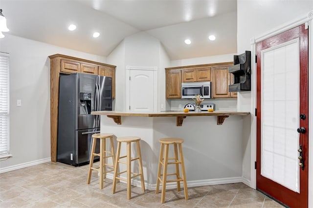 kitchen featuring a breakfast bar area, kitchen peninsula, lofted ceiling, and appliances with stainless steel finishes