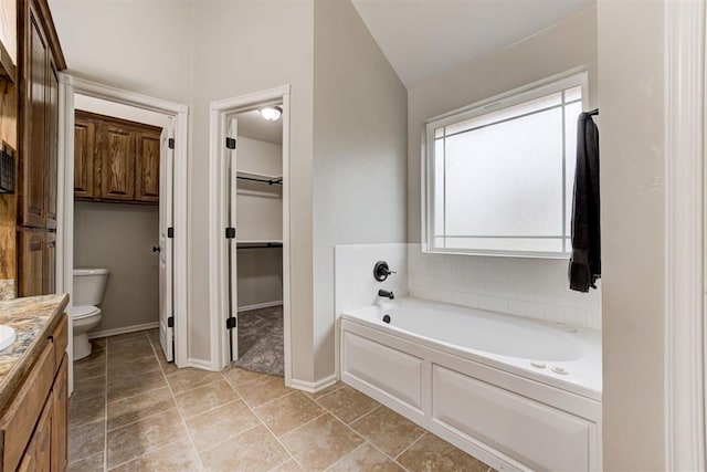 bathroom featuring a washtub, toilet, lofted ceiling, and vanity