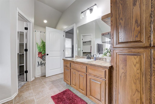 bathroom with tile patterned floors, vanity, and lofted ceiling