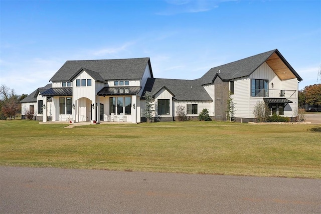 modern farmhouse style home with a front yard and a balcony