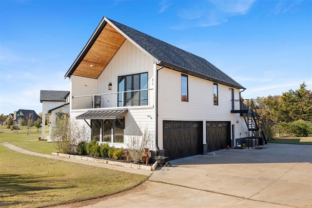 view of side of property with a lawn, a garage, and a balcony