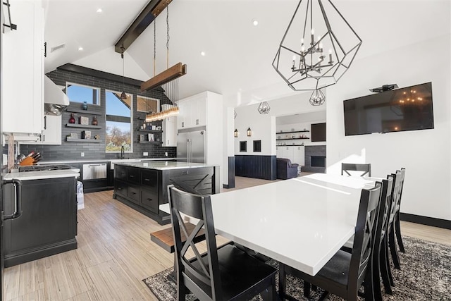 dining area with lofted ceiling with beams, light hardwood / wood-style flooring, and sink