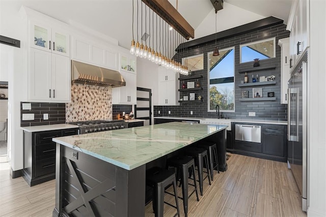 kitchen with ventilation hood, hanging light fixtures, tasteful backsplash, a kitchen island, and white cabinetry