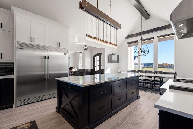 kitchen featuring white cabinets, hanging light fixtures, built in refrigerator, a kitchen island, and beam ceiling