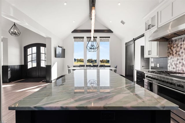 kitchen featuring dark wood-type flooring, a large island, light stone counters, white cabinetry, and extractor fan