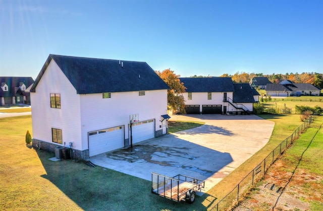 back of house featuring central air condition unit, a garage, and a lawn