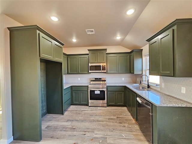 kitchen featuring green cabinets, sink, stainless steel appliances, and vaulted ceiling