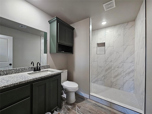 bathroom featuring tiled shower, vanity, and toilet