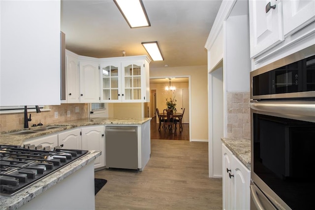 kitchen with white cabinetry, sink, stainless steel appliances, light hardwood / wood-style flooring, and backsplash