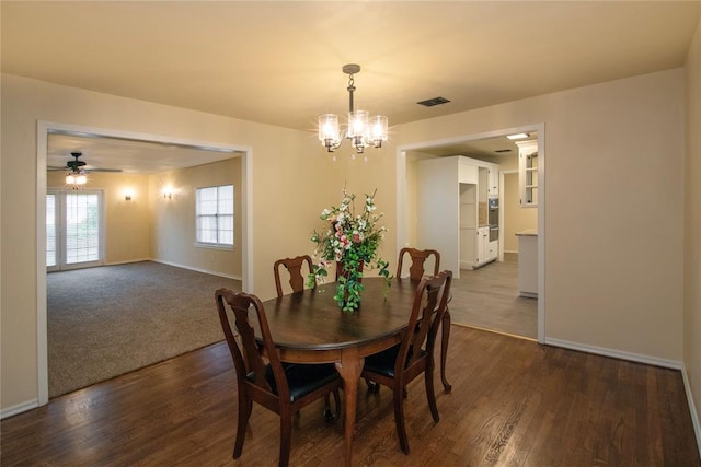 dining area featuring ceiling fan with notable chandelier and dark wood-type flooring