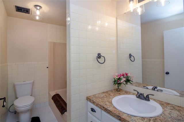 bathroom with tile patterned flooring, vanity, toilet, and tile walls