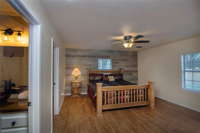 bedroom featuring hardwood / wood-style flooring, ceiling fan, and wooden walls