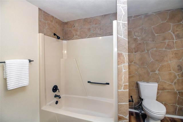 bathroom with wood-type flooring, a textured ceiling, shower / bath combination, and toilet