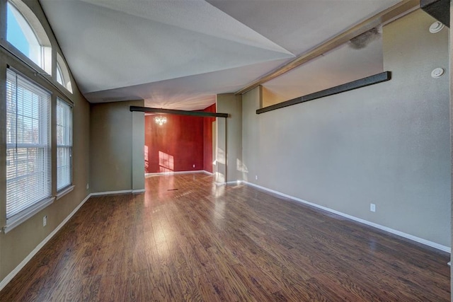 empty room with dark wood-type flooring and high vaulted ceiling