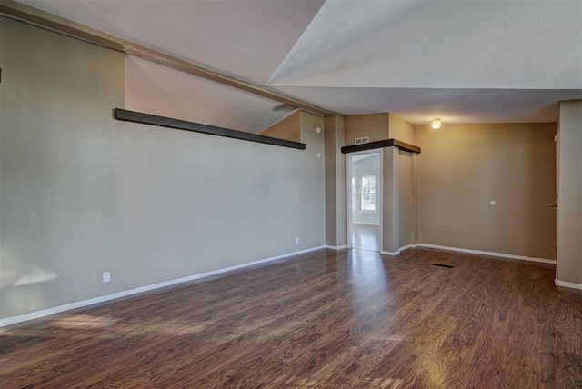 spare room with dark wood-type flooring and vaulted ceiling