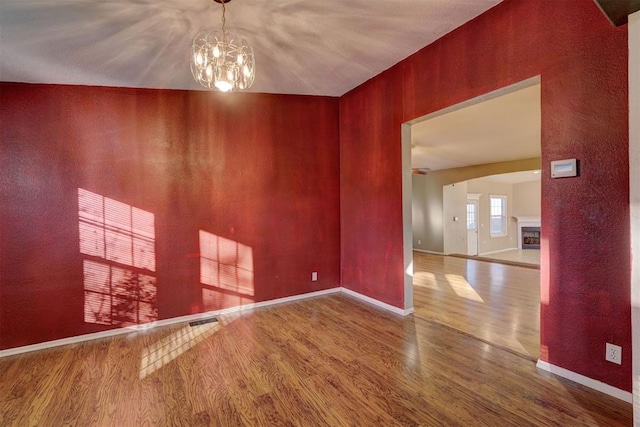 unfurnished room featuring hardwood / wood-style floors, a chandelier, and lofted ceiling