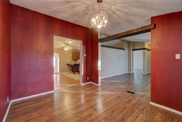 unfurnished room featuring ceiling fan with notable chandelier, hardwood / wood-style flooring, and wooden walls