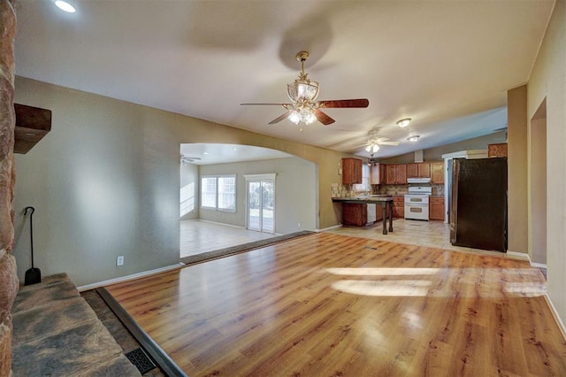 kitchen with lofted ceiling, white range, light wood-type flooring, and fridge