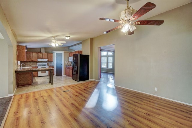 kitchen with lofted ceiling, black refrigerator, light hardwood / wood-style floors, and white stove