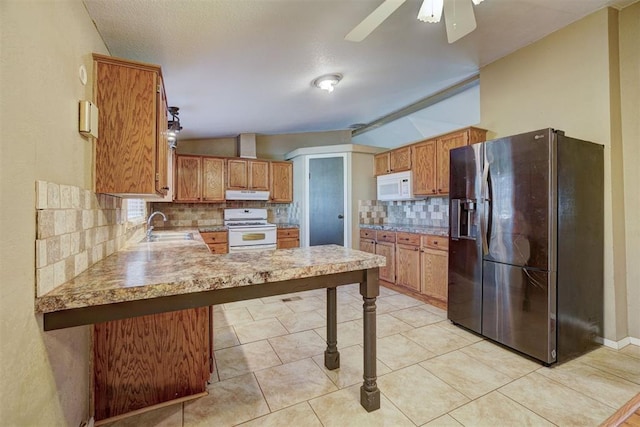 kitchen with white appliances, backsplash, ceiling fan, a kitchen bar, and kitchen peninsula