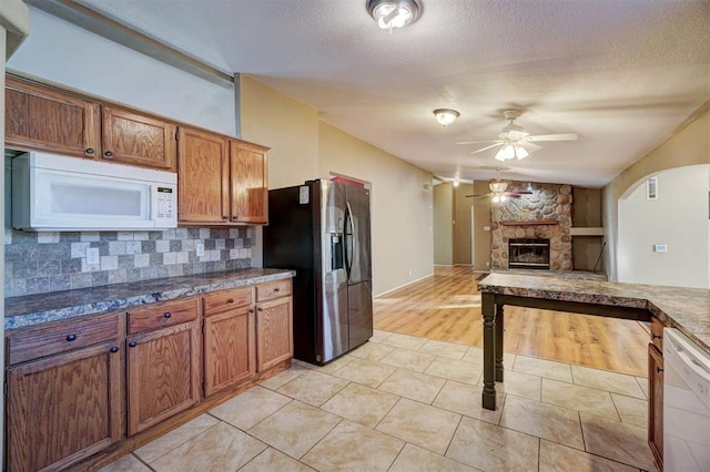 kitchen featuring white appliances, ceiling fan, light wood-type flooring, a fireplace, and tasteful backsplash