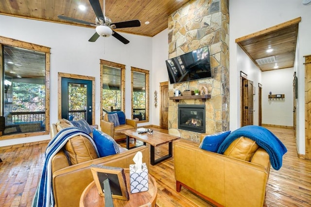 living room with light hardwood / wood-style floors, wooden ceiling, a fireplace, and high vaulted ceiling