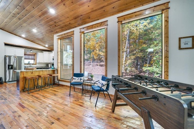 kitchen featuring a kitchen breakfast bar, a healthy amount of sunlight, white cabinetry, and stainless steel refrigerator with ice dispenser