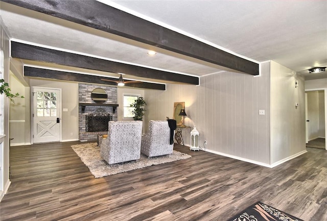 living room with wood walls, dark hardwood / wood-style floors, beam ceiling, and a fireplace