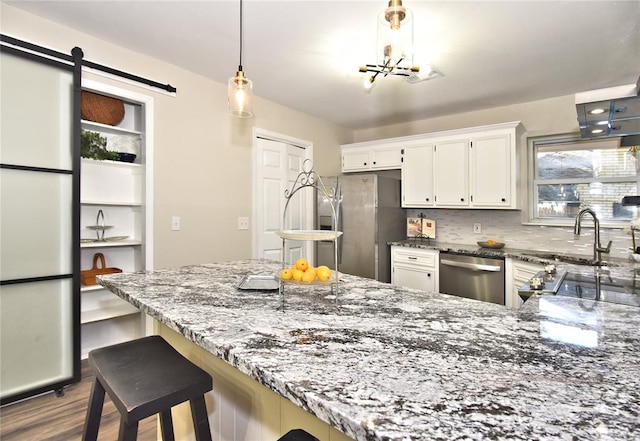 kitchen featuring a kitchen bar, appliances with stainless steel finishes, decorative backsplash, a barn door, and white cabinets