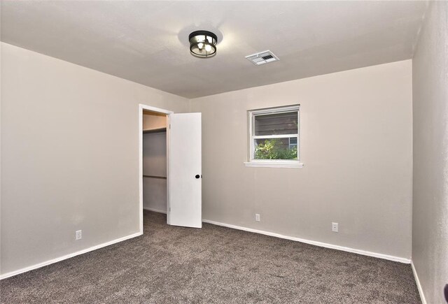 unfurnished bedroom featuring dark colored carpet and a closet