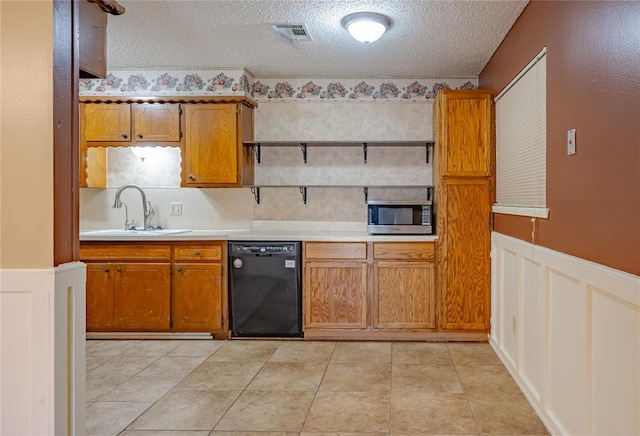 kitchen with a textured ceiling, light tile patterned flooring, sink, and black dishwasher