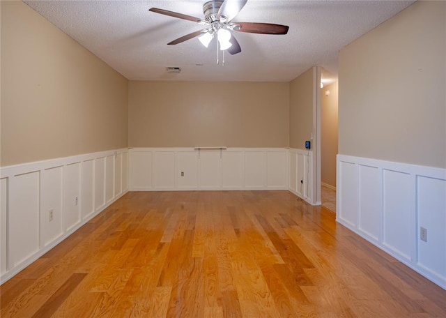 spare room with a textured ceiling, light hardwood / wood-style floors, and ceiling fan