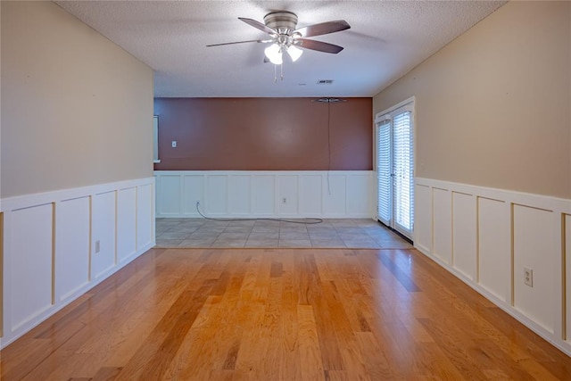 unfurnished room featuring ceiling fan, a textured ceiling, and light hardwood / wood-style flooring