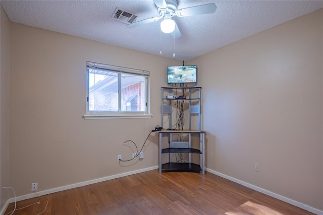 empty room with ceiling fan, hardwood / wood-style floors, and a textured ceiling