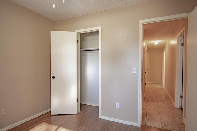 unfurnished bedroom with a textured ceiling, light hardwood / wood-style flooring, and a closet