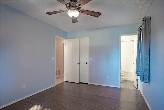 unfurnished bedroom with a textured ceiling, dark hardwood / wood-style floors, ceiling fan, and ensuite bathroom